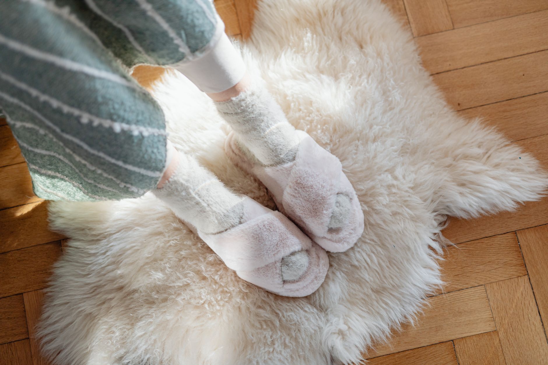 pieds portant des chaussons en peau de mouton sur un tapis douillet dans un intérieur chaleureux, avec une lumière douce d’hiver